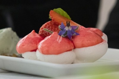 Portion de viande braisée servie dans une petite coupelle, garnie de pousses rouges.