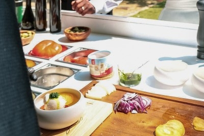 Plat gastronomique composé d'une mousse verte, surmontée de saumon et de pousses, présenté dans une assiette blanche.