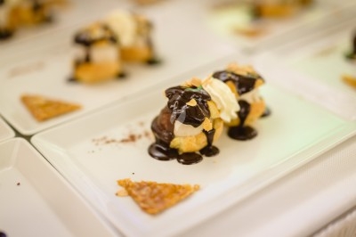 Plat gastronomique composé d'une mousse verte, surmontée de saumon et de pousses, présenté dans une assiette blanche.