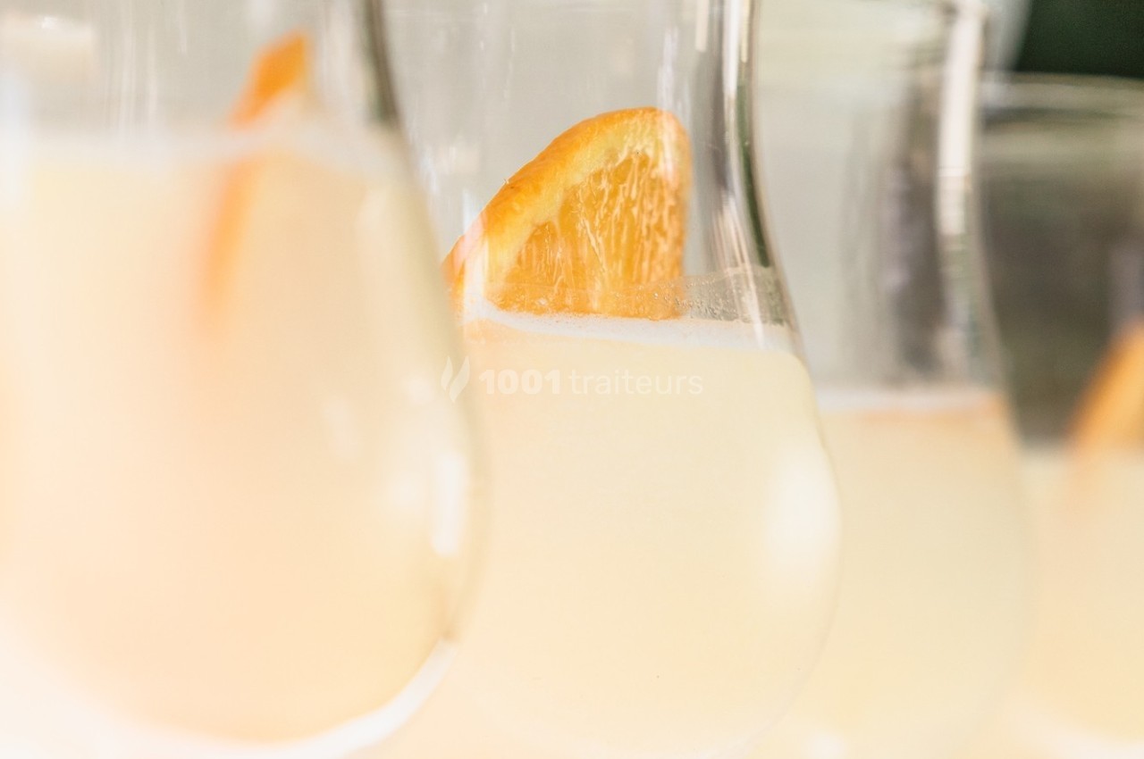 Verres de cocktail clair garnis de tranches d'orange, photographiés en gros plan avec une lumière douce.