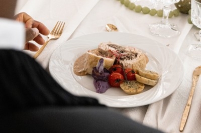 Plat gastronomique composé d'une mousse verte, surmontée de saumon et de pousses, présenté dans une assiette blanche.