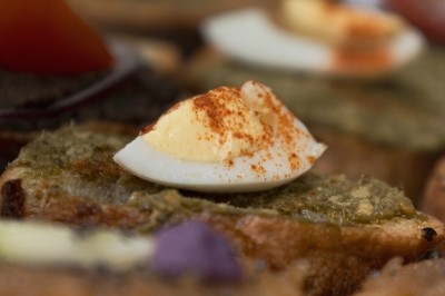 Plat gastronomique composé d'une mousse verte, surmontée de saumon et de pousses, présenté dans une assiette blanche.