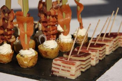 Miniature Traiteur Garancières (Yvelines) - Havane Traiteur #12 Table dressée avec nappes blanches, couverts, menus et bouquets de fleurs, entourée de chaises en bois dans une salle.