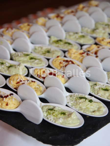 Cuillères en porcelaine blanche garnies de préparations crémeuses variées, disposées sur un plateau noir.