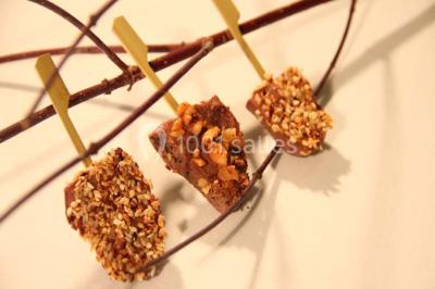 Table dressée avec nappes blanches, couverts, menus et bouquets de fleurs, entourée de chaises en bois dans une salle.