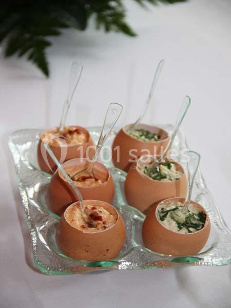 Œufs coquilles garnis de différentes préparations crémeuses, présentés sur un plateau en verre avec des cuillères.