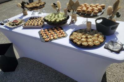 Un serveur remplit un verre de boisson pour un homme lors d'un buffet avec des verrines et des invités en arrière-plan.