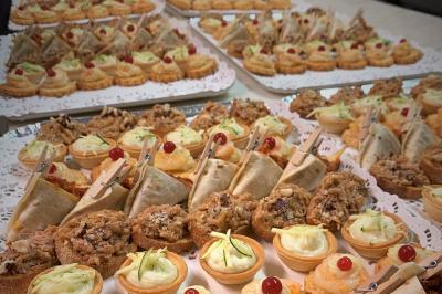 Un serveur remplit un verre de boisson pour un homme lors d'un buffet avec des verrines et des invités en arrière-plan.