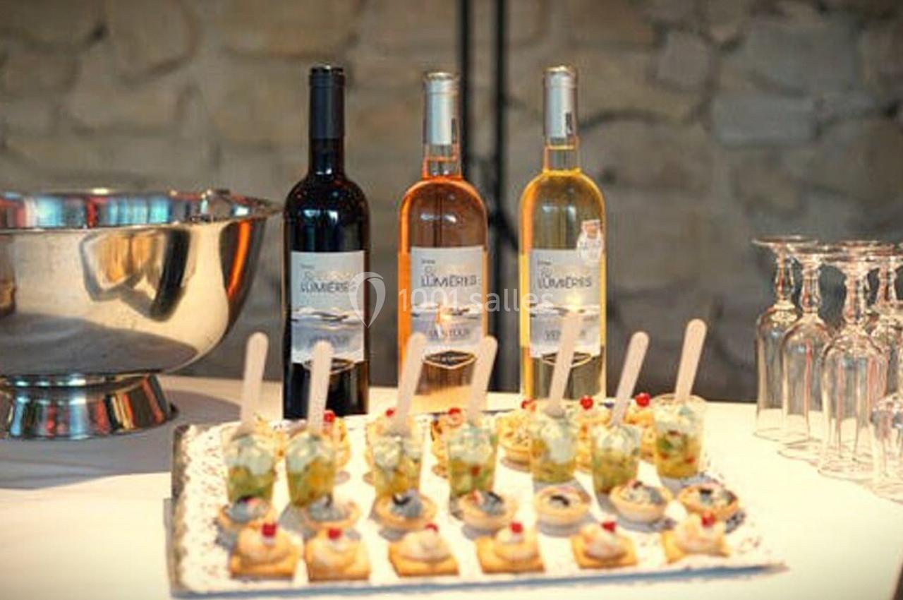 Plateau de verrines et amuse-bouches devant trois bouteilles de vin rouge, rosé et blanc, avec des verres à pied à côté.