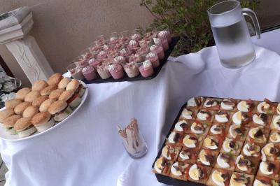 Un serveur remplit un verre de boisson pour un homme lors d'un buffet avec des verrines et des invités en arrière-plan.