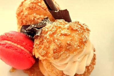 Un serveur remplit un verre de boisson pour un homme lors d'un buffet avec des verrines et des invités en arrière-plan.