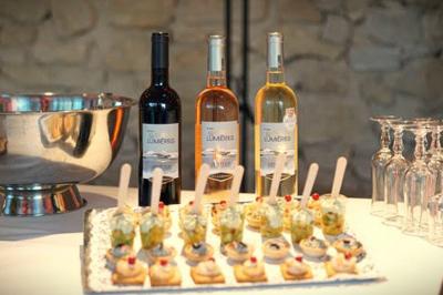 Un serveur remplit un verre de boisson pour un homme lors d'un buffet avec des verrines et des invités en arrière-plan.