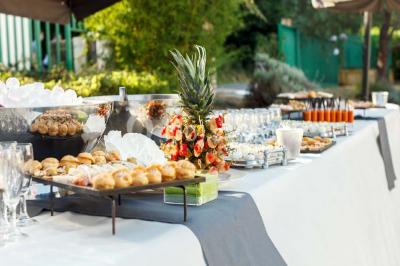 Une main coupe un rouleau de foie gras sur une planche en bois, entouré de figues et de tomates cerises.