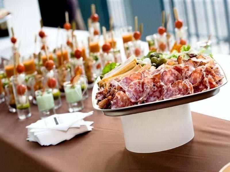 Plateau de charcuterie avec olives et gressins au premier plan, accompagné de verrines en arrière-plan.