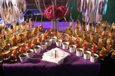 Une main coupe un rouleau de foie gras sur une planche en bois, entouré de figues et de tomates cerises.