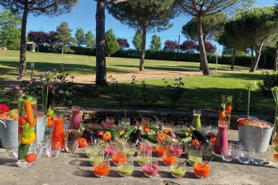 Une main coupe un rouleau de foie gras sur une planche en bois, entouré de figues et de tomates cerises.