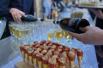 Une main coupe un rouleau de foie gras sur une planche en bois, entouré de figues et de tomates cerises.