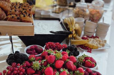 Une main coupe un rouleau de foie gras sur une planche en bois, entouré de figues et de tomates cerises.