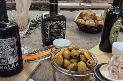 Une main coupe un rouleau de foie gras sur une planche en bois, entouré de figues et de tomates cerises.