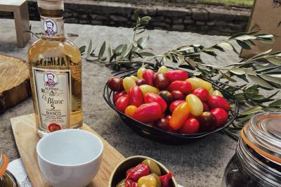 Une main coupe un rouleau de foie gras sur une planche en bois, entouré de figues et de tomates cerises.