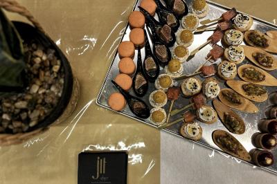 Une main coupe un rouleau de foie gras sur une planche en bois, entouré de figues et de tomates cerises.