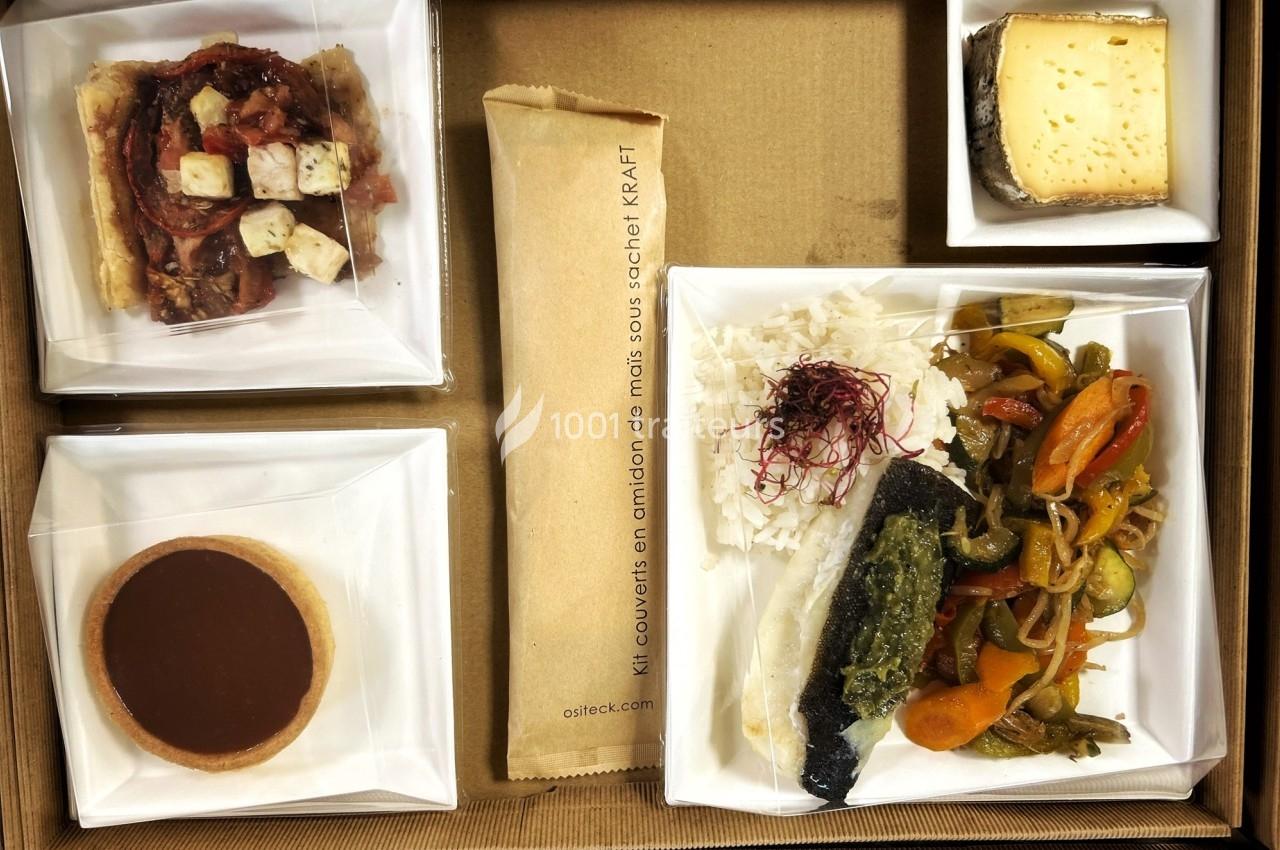 Plateau-repas composé de poisson, légumes, riz, tartelette, fromage, pain et couverts emballés dans un sachet kraft.