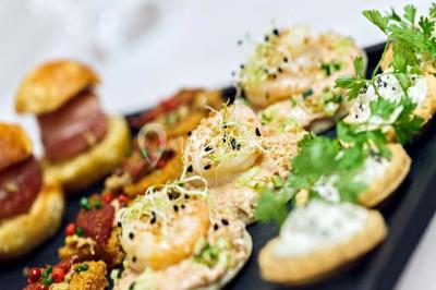 Miniature Traiteur Chaponost (Rhône) - Jacques Lafargue Traiteur #17 Une main coupe un rouleau de foie gras sur une planche en bois, entouré de figues et de tomates cerises.