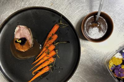 Miniature Traiteur Chaponost (Rhône) - Jacques Lafargue Traiteur #7 Une main coupe un rouleau de foie gras sur une planche en bois, entouré de figues et de tomates cerises.