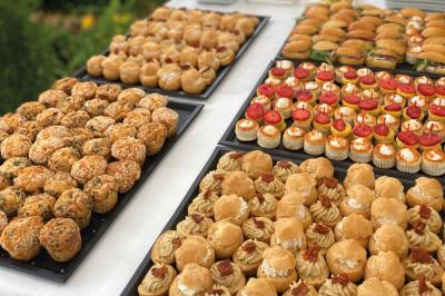 Miniature Traiteur Chaponost (Rhône) - Jacques Lafargue Traiteur #2 Une main coupe un rouleau de foie gras sur une planche en bois, entouré de figues et de tomates cerises.