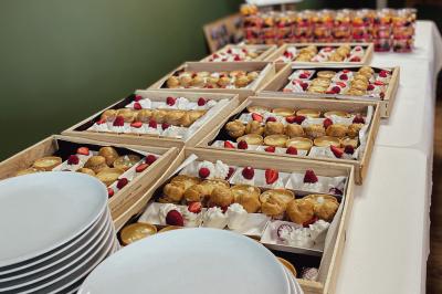 Miniature Traiteur Chaponost (Rhône) - Jacques Lafargue Traiteur #15 Une main coupe un rouleau de foie gras sur une planche en bois, entouré de figues et de tomates cerises.