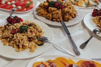 Miniature Traiteur Chaponost (Rhône) - Jacques Lafargue Traiteur #16 Une main coupe un rouleau de foie gras sur une planche en bois, entouré de figues et de tomates cerises.