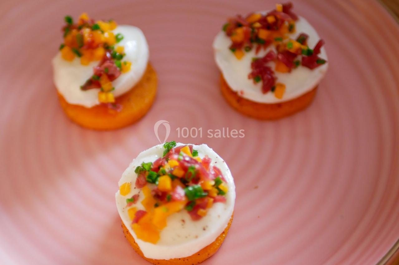 Trois bouchées sur un plat rose, composées de rondelles de patate douce, crème et garniture colorée.