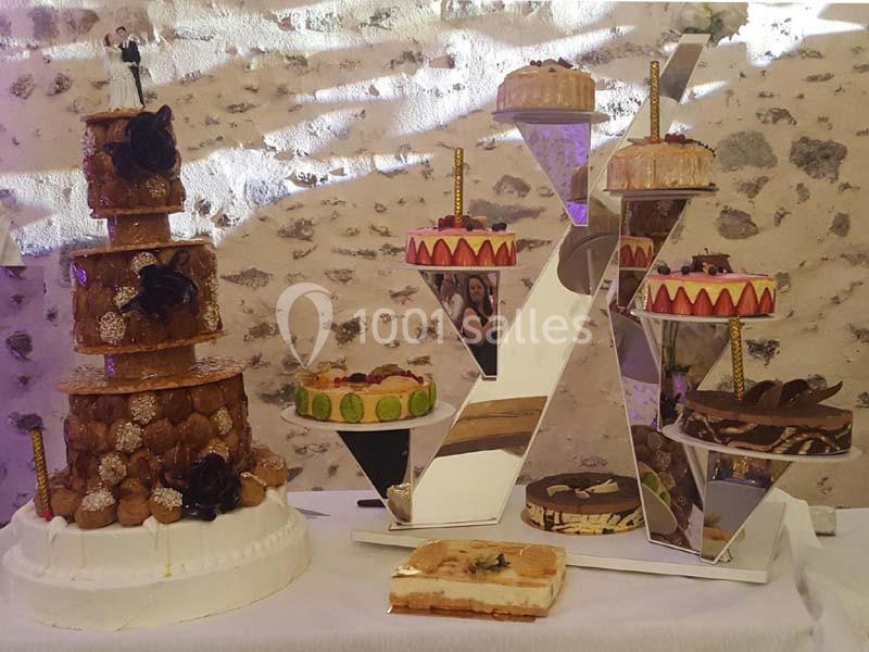 Pièce montée en choux et assortiment de gâteaux variés présentés sur une table décorée devant un mur en pierre.