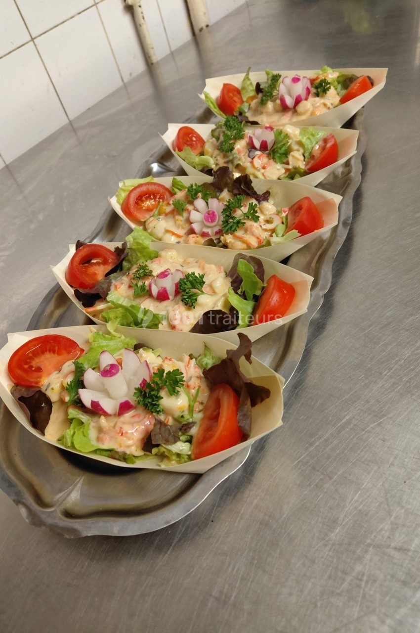 Plateau de barquettes garnies de salade, tomates, radis et persil, disposées sur un plan de travail en inox.