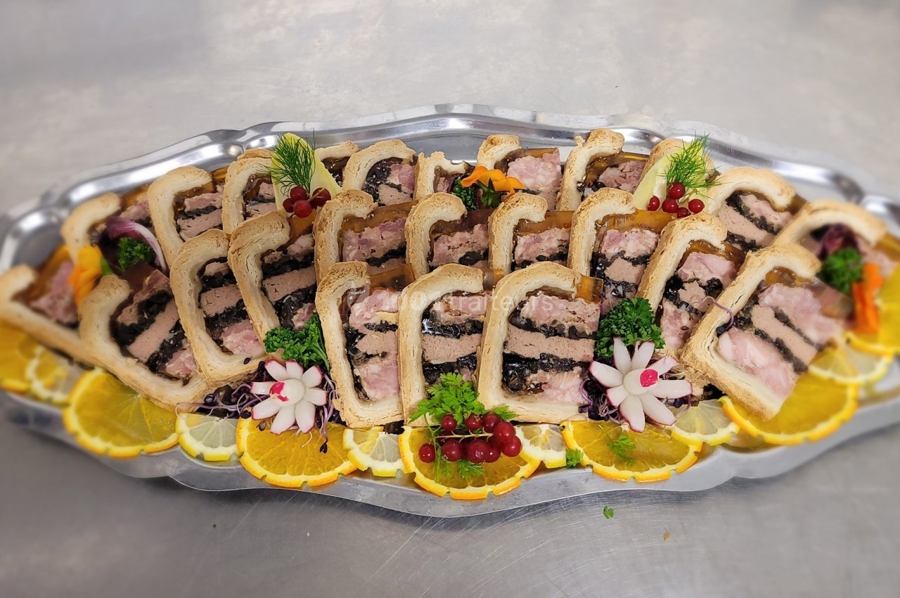 Plateau de pâtés en croûte garnis de tranches d'orange, de groseilles et de décorations végétales.