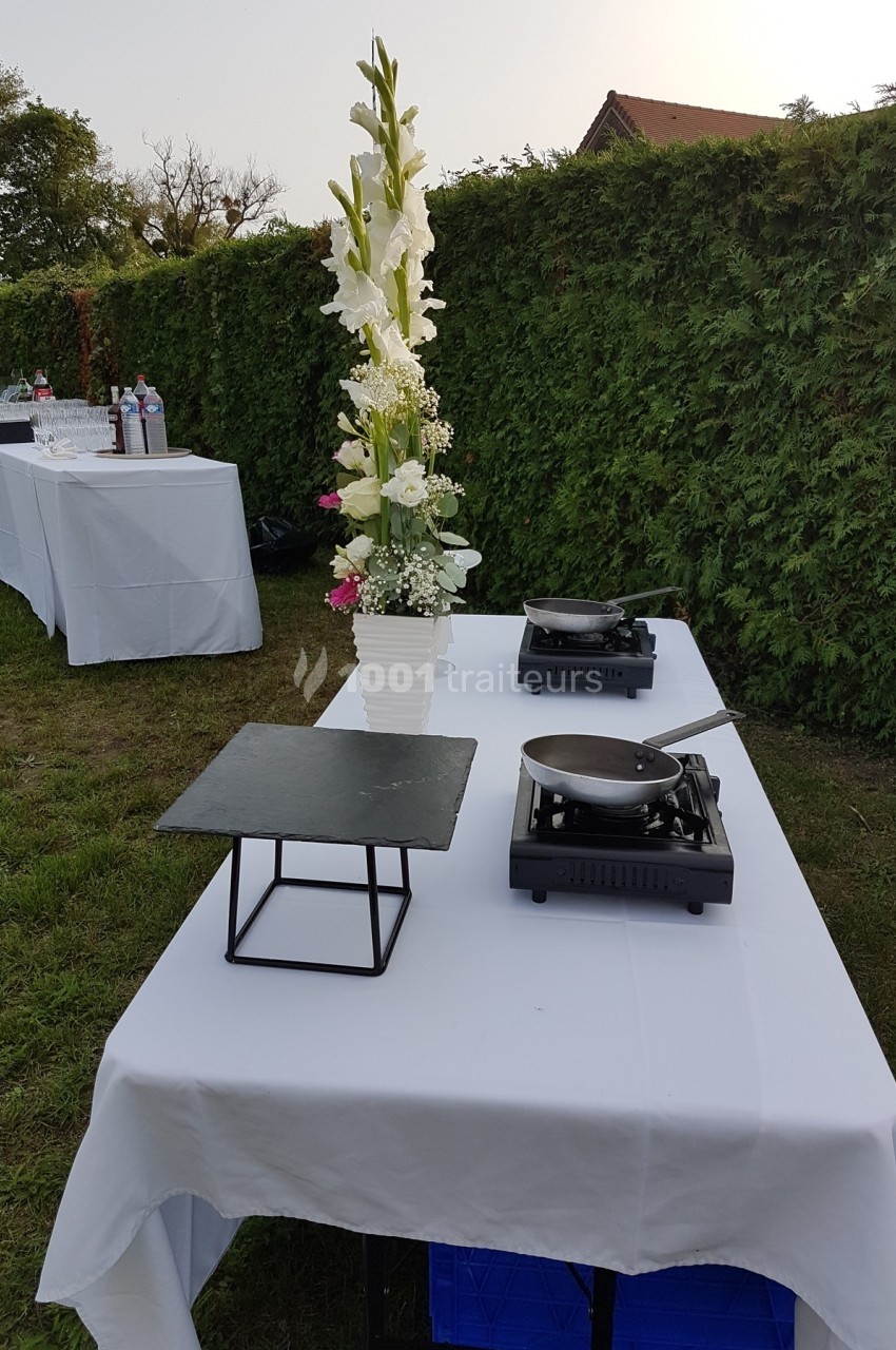 Table dressée en extérieur avec une décoration florale, des réchauds et une assiette en ardoise.