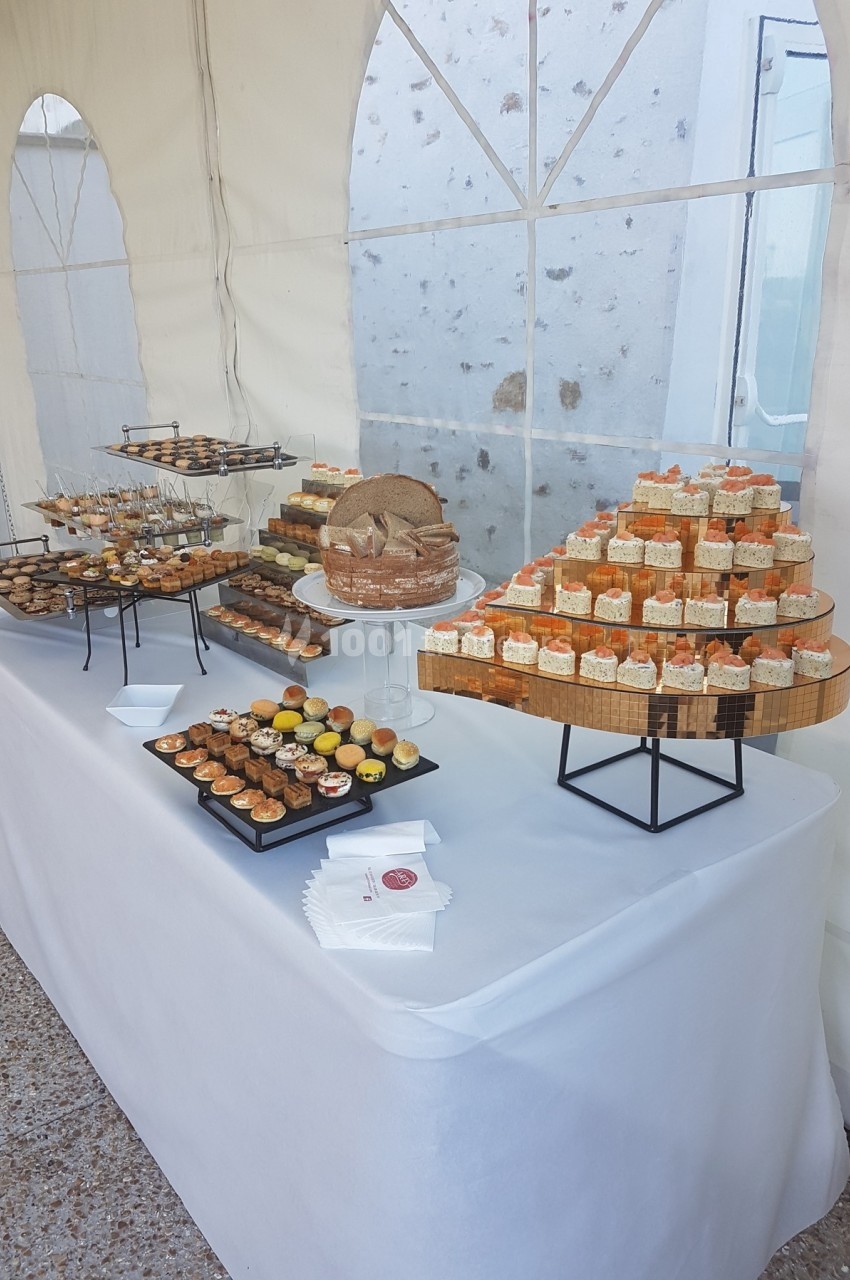 Table garnie de pâtisseries variées disposées sur des présentoirs dans une tente lumineuse.