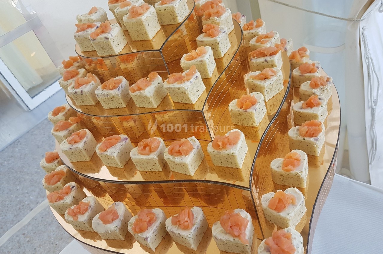 Plateau de bouchées apéritives en forme de cœur, garnies de mousse et de saumon, disposées sur plusieurs niveaux.