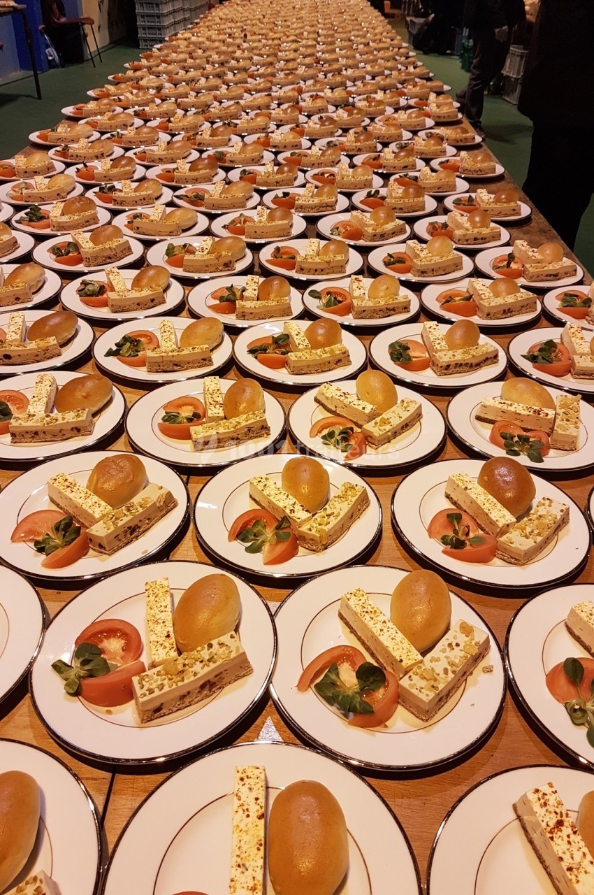 Des assiettes identiques alignées avec un dessert composé de brioche, nougat glacé et garniture de fruits.