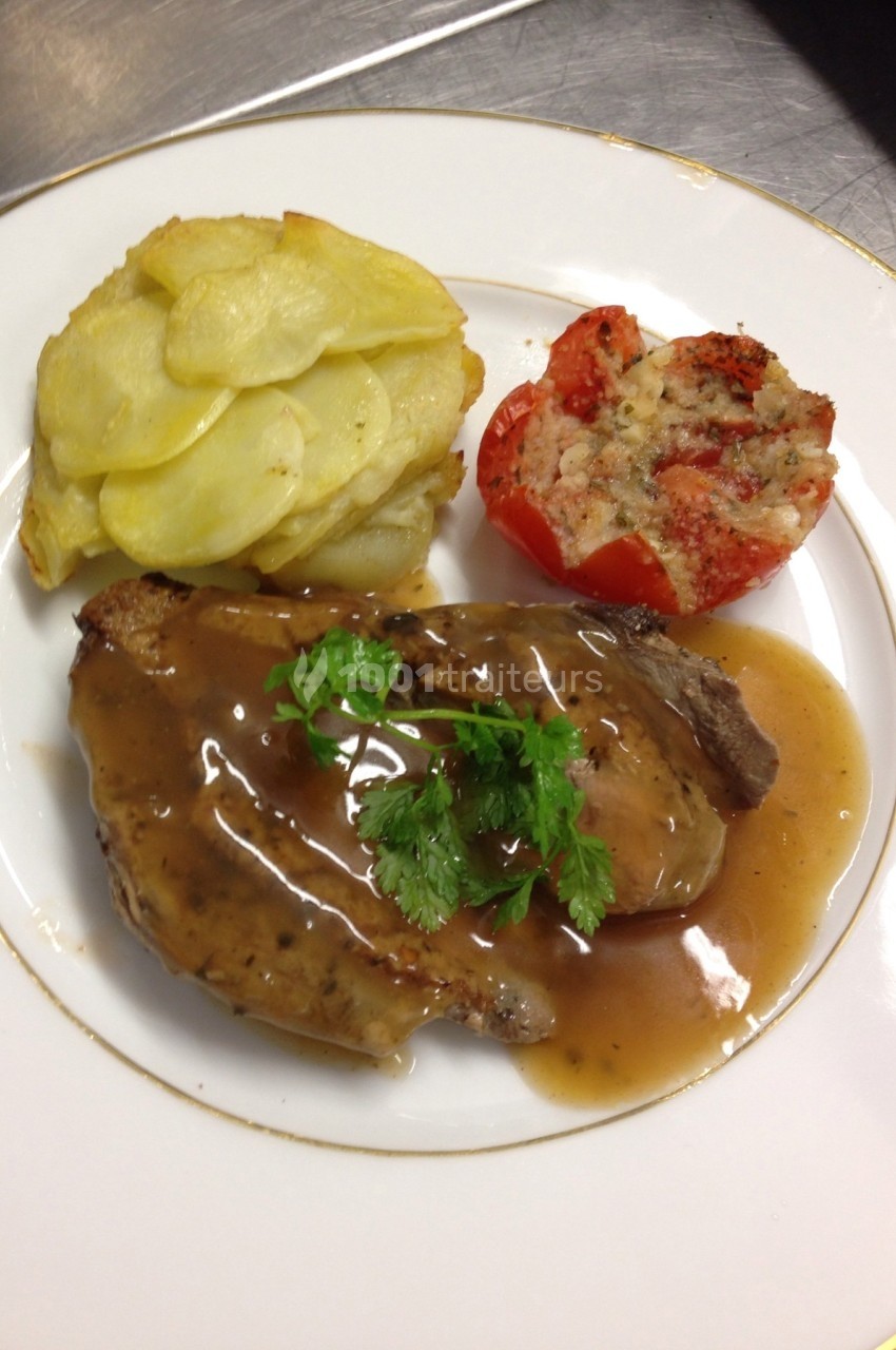 Assiette contenant une tranche de viande nappée de sauce, accompagnée de gratin de pommes de terre et d'une tomate farcie.