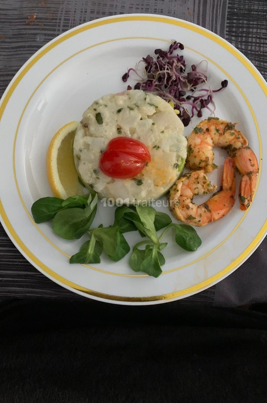 Assiette avec un tartare de poisson, crevettes marinées, roquette, citron, tomate cerise et pousses de radis.