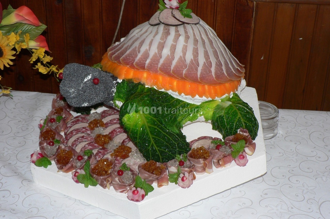 Présentation culinaire en forme de tortue, composée de légumes, charcuterie et garnitures décoratives.