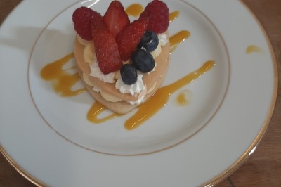 Assiette composée de foie gras, gelée, pain brioché, tranches d'orange, groseilles, jeunes pousses et graines noires.