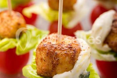 Dessert au chocolat brillant orné de feuille d'or, posé sur une base avec éclats de cacao, sur fond sombre.