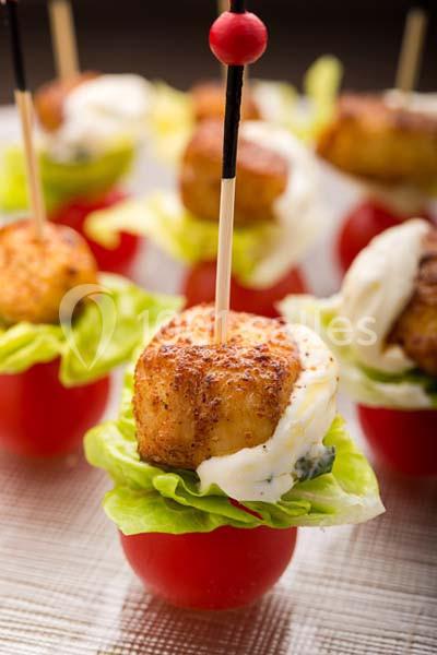 Bouchées apéritives composées de tomates, feuilles de laitue, fromage et pétoncles grillés sur des piques en bois.