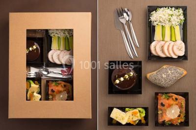 Dessert au chocolat brillant orné de feuille d'or, posé sur une base avec éclats de cacao, sur fond sombre.