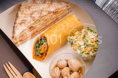 Dessert au chocolat brillant orné de feuille d'or, posé sur une base avec éclats de cacao, sur fond sombre.