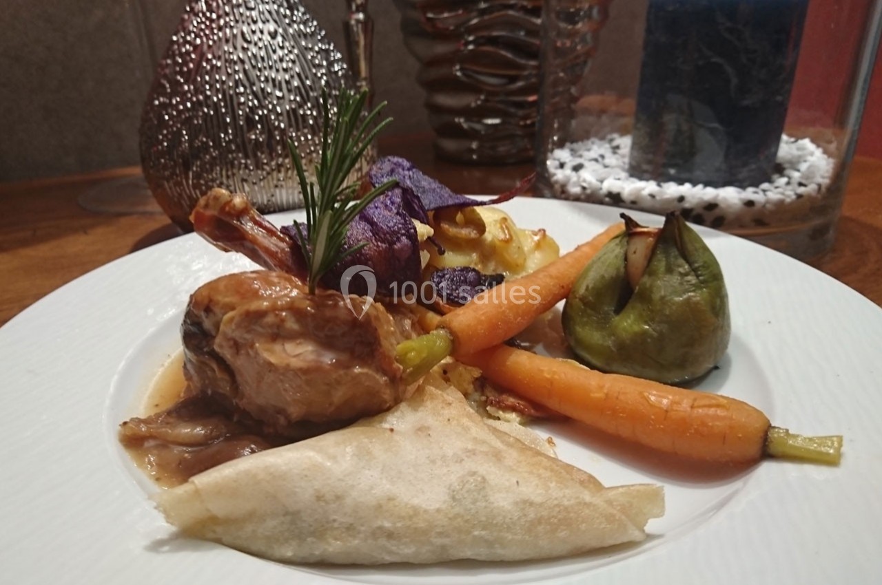 Assiette gastronomique composée de viande en sauce, légumes variés, samoussa et décoration raffinée.