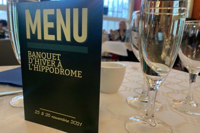 Salle de réception éclairée en bleu avec des tables rondes dressées et des écrans disposés autour.