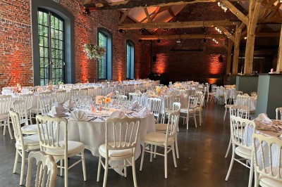 Salle de réception éclairée en bleu avec des tables rondes dressées et des écrans disposés autour.